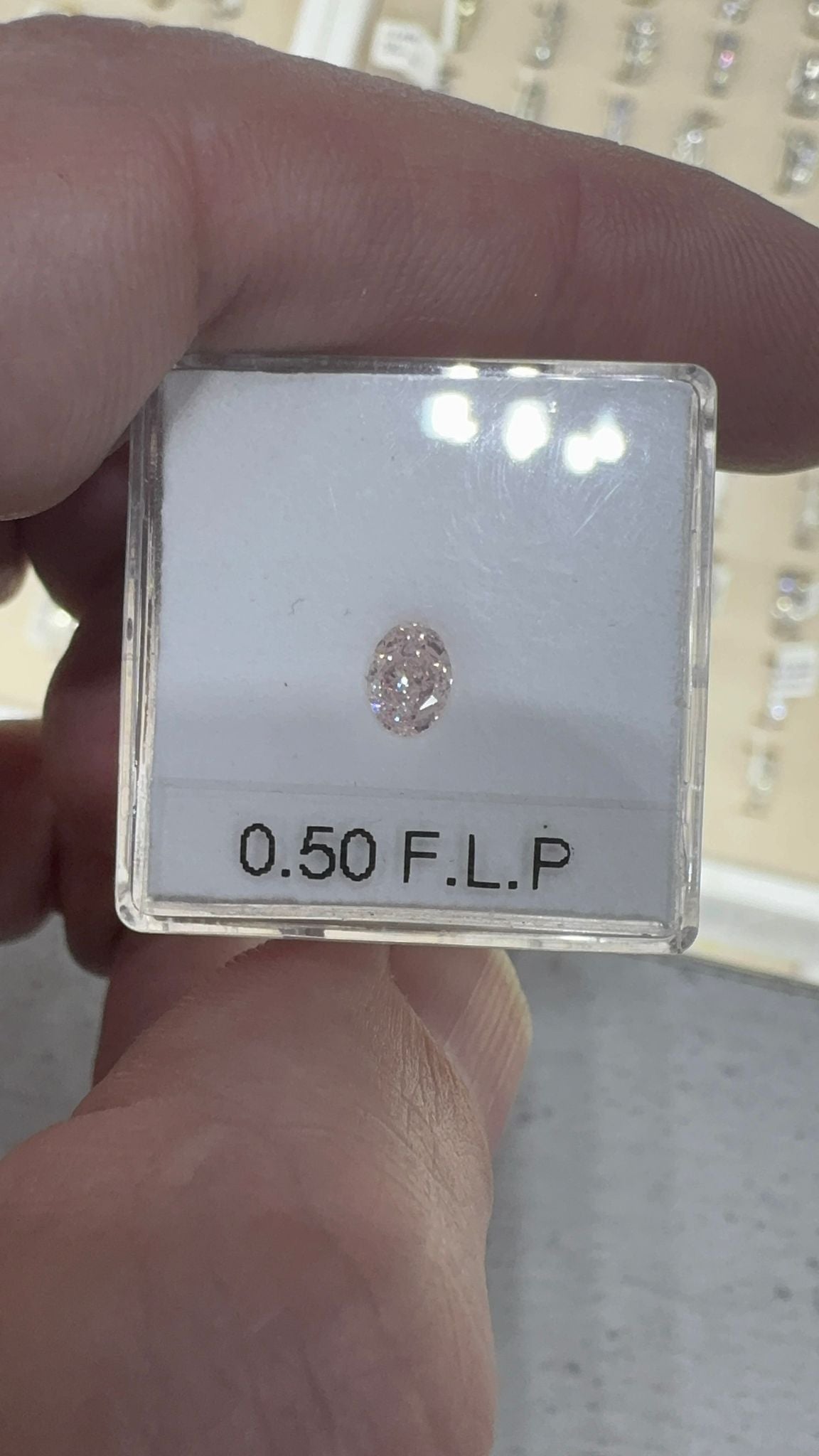 Diamond in a clear box with '0.50 F.L.P.' label held by a hand.