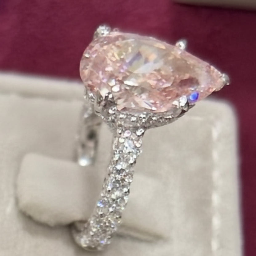 Diamond ring with a pink pear cut on a branded cushion