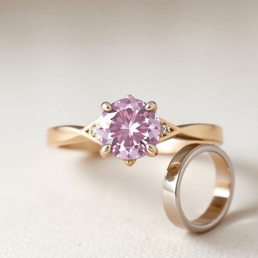 Close-up of a sparkling pink diamond in a ring with rose gold, yellow gold, and platinum bands on a soft neutral background.