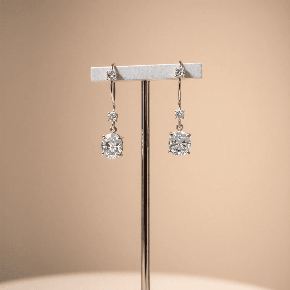 Close-up of sparkling diamond earrings on a sleek stand with soft lighting against a neutral background.
