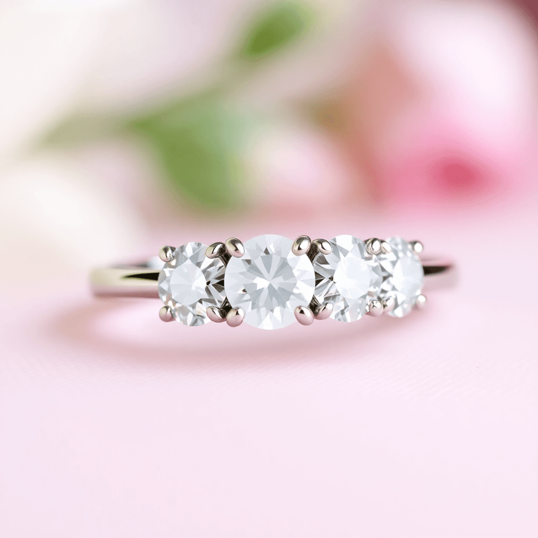 Close-up of an elegant three-stone diamond engagement ring on a soft, romantic background.