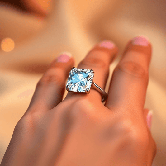 Close-up of a sparkling cushion cut diamond engagement ring on a slender hand with warm, soft lighting highlighting the diamond’s brilliance.