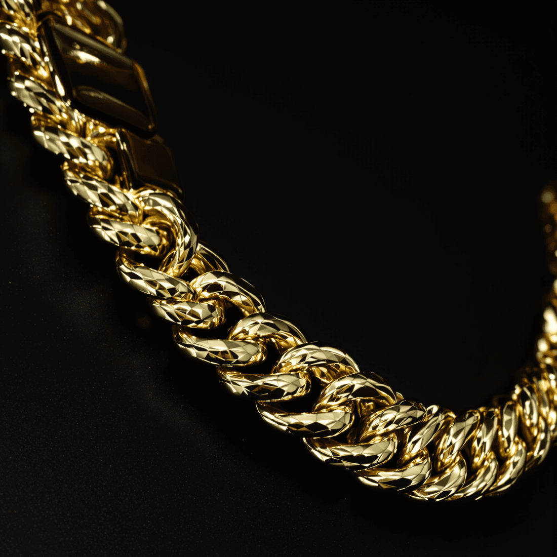 Close-up of a thick, shiny gold Cuban link chain with interlocking oval links on a sleek black background.