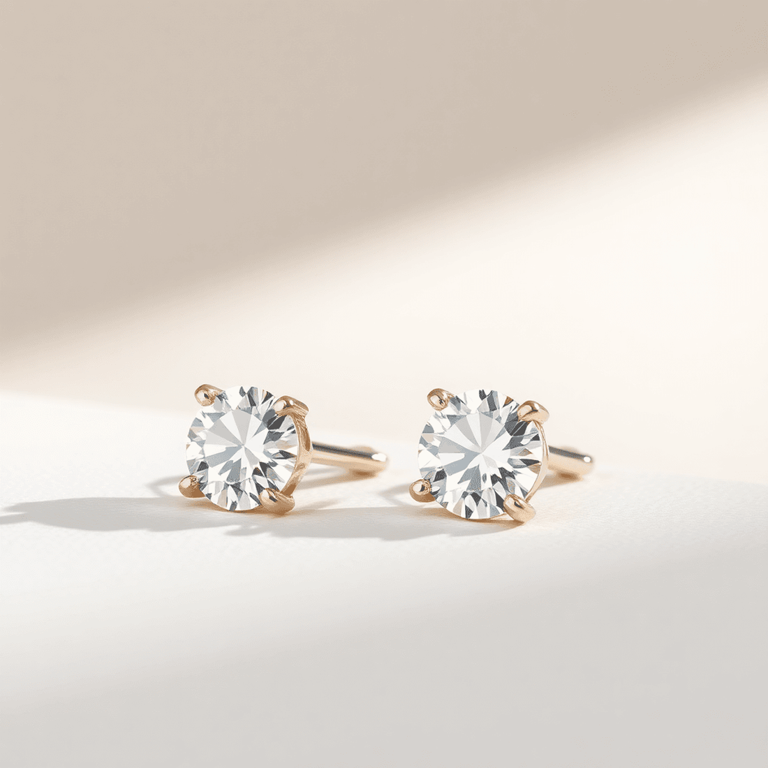 Close-up of sparkling diamond stud earrings on a neutral background, highlighting their elegance and timeless beauty in soft natural light.