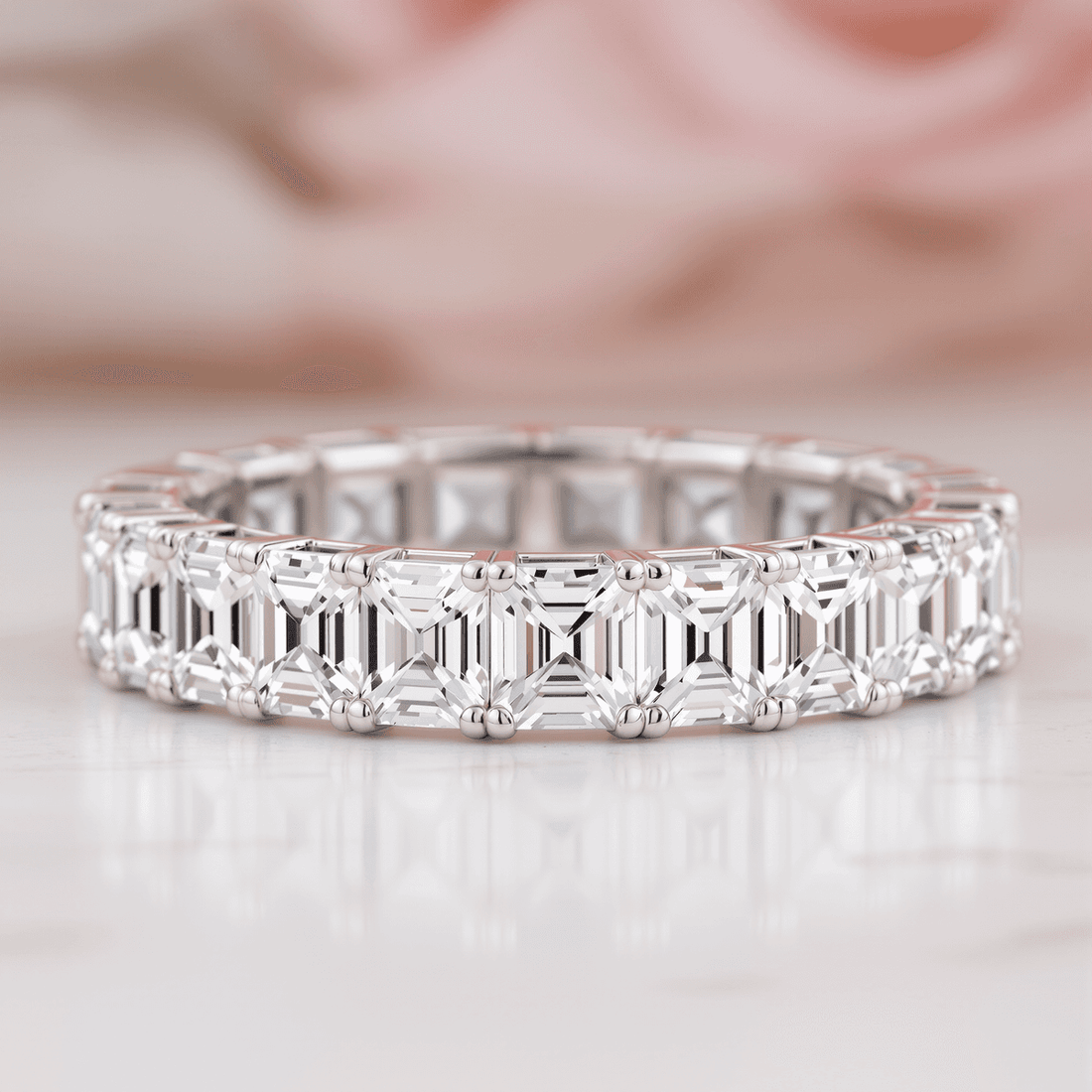 Close-up of a sparkling Asscher cut diamond eternity band with square shape and step facets against a soft vintage background.