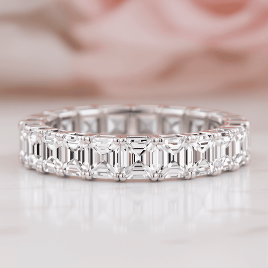 Close-up of a sparkling Asscher cut diamond eternity band with square shape and step facets against a soft vintage background.