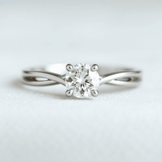 Close-up of an elegant split shank engagement ring with a sparkling center diamond on a soft, blurred background.