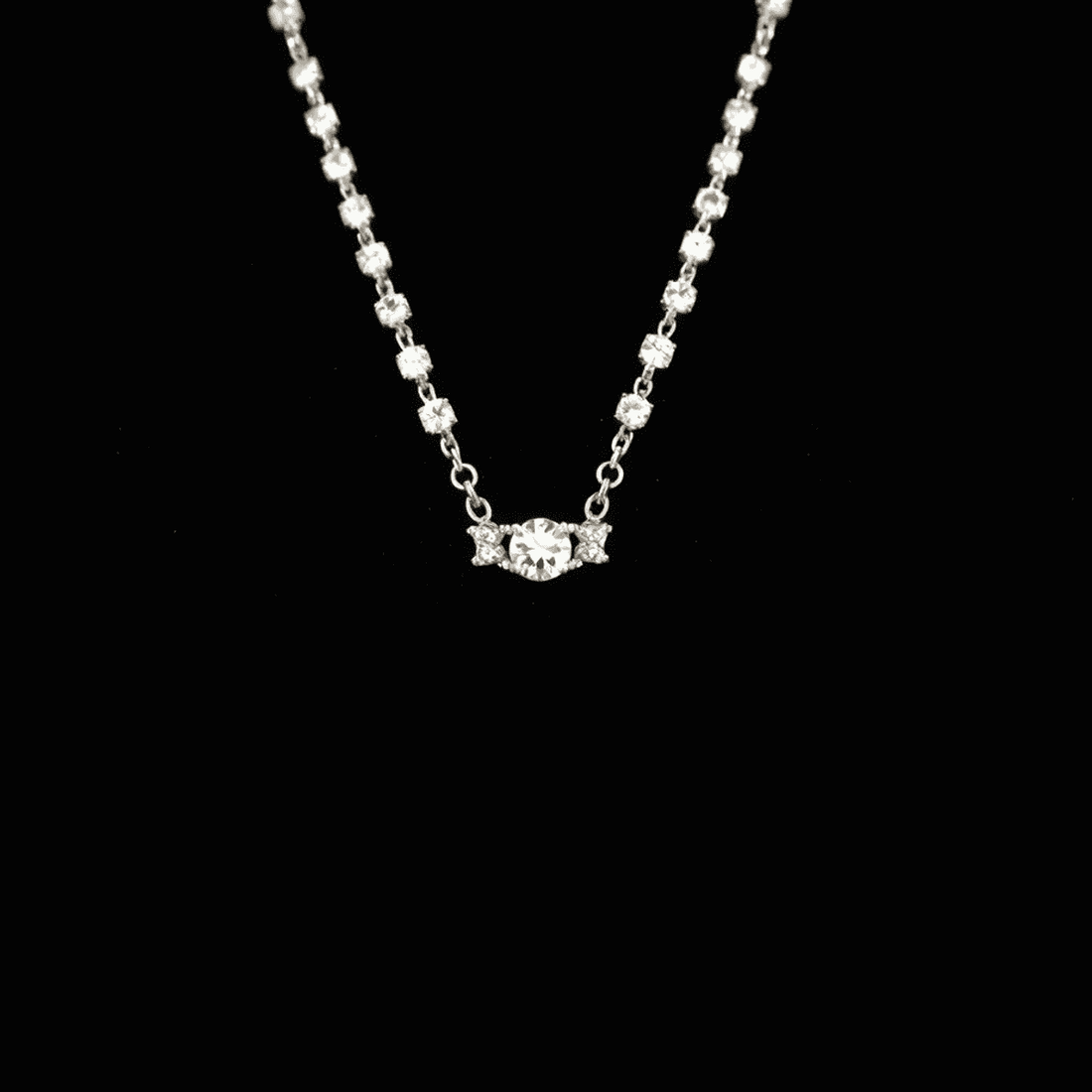 Close-up of a sparkling tennis diamond necklace on black velvet display, highlighting its continuous row of brilliant diamonds.