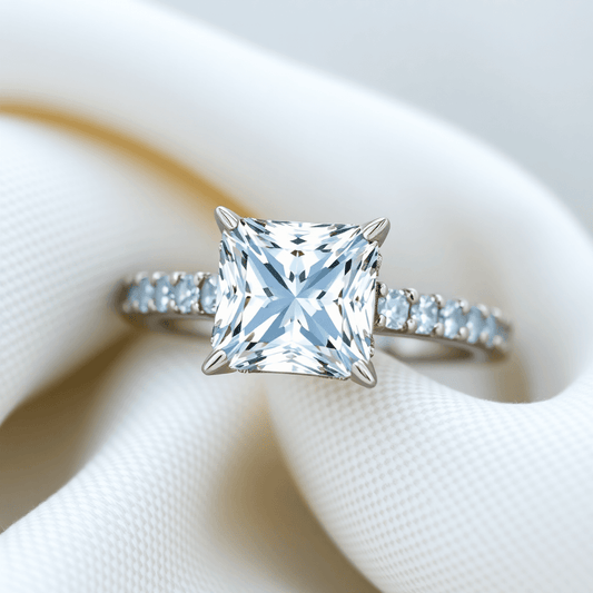 Close-up of a sparkling princess cut diamond ring with a diamond-studded band on soft fabric, highlighting the brilliance and elegance of the diamonds.