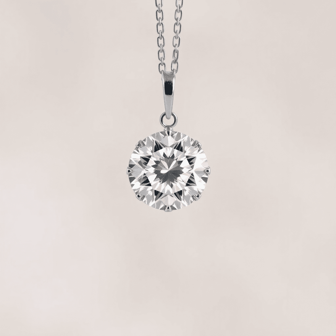 Close-up of a sparkling round brilliant diamond pendant on a delicate chain, glowing with radiant light reflections against a soft, blurred neutral background.