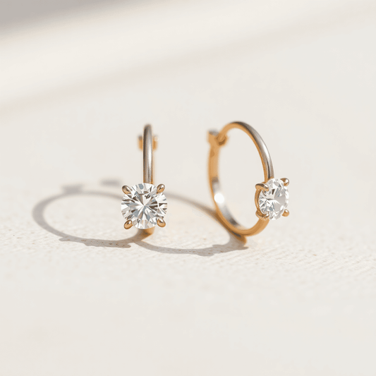 Close-up of sparkling diamond hoop earrings on a textured neutral background, highlighting their intricate details and elegant brilliance.