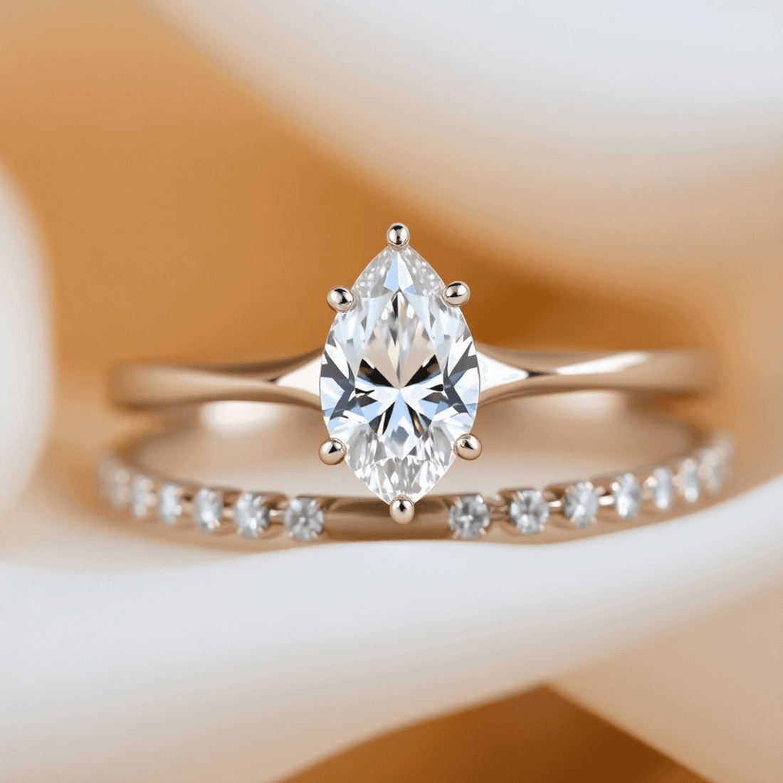 Close-up of a sparkling pear-cut diamond engagement ring paired with elegant wedding bands on a soft, romantic background with gentle lighting.