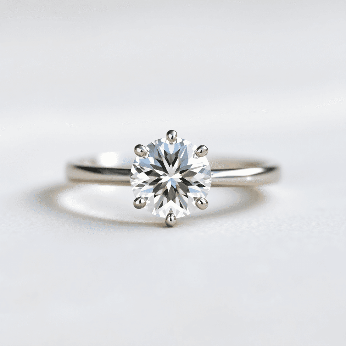 Close-up of a sparkling round-cut solitaire diamond ring on a soft neutral background with light reflections highlighting its brilliance and clarity.