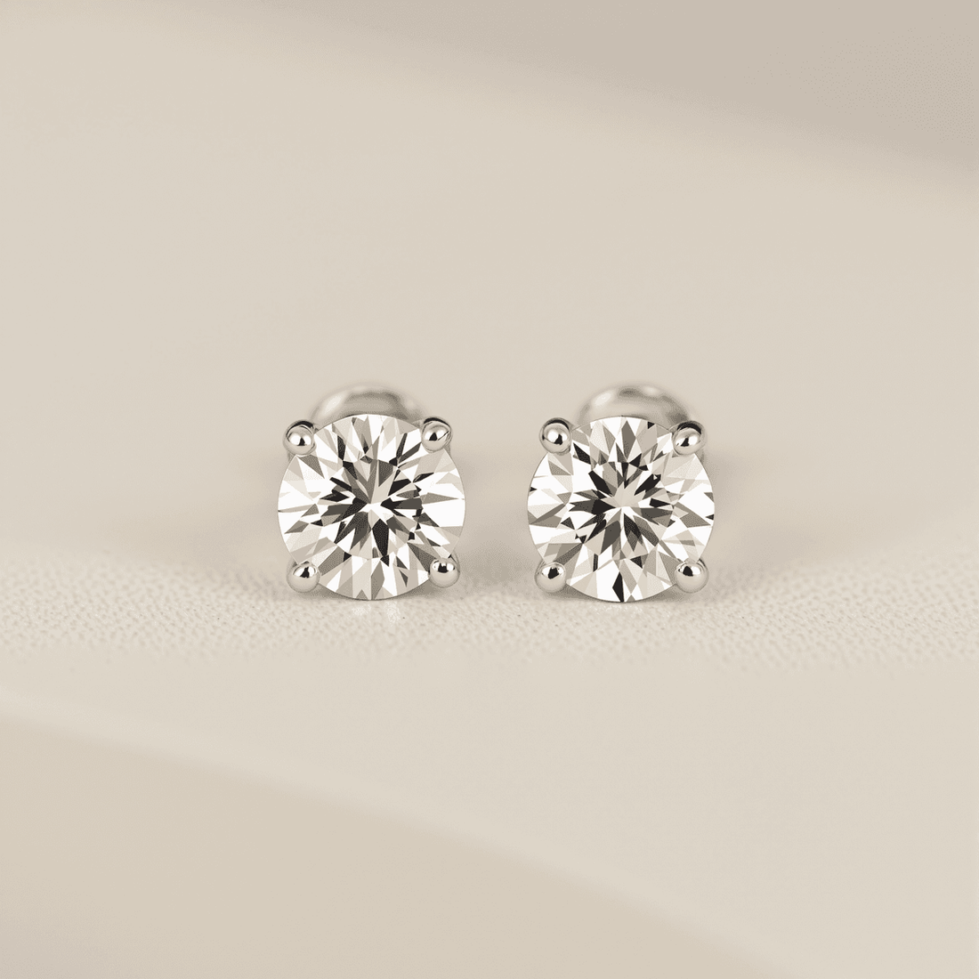 Close-up of sparkling diamond stud earrings on a soft, neutral background showcasing their minimalist and timeless design.