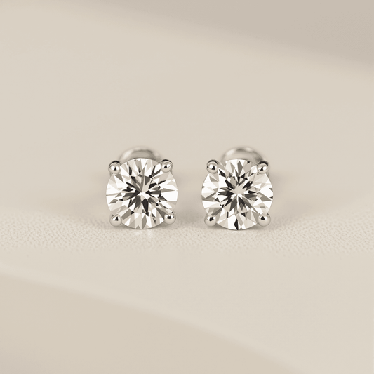 Close-up of sparkling diamond stud earrings on a soft, neutral background showcasing their minimalist and timeless design.