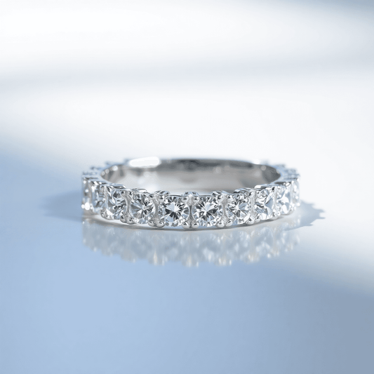 Close-up of a sparkling lab-grown diamond eternity band on a reflective surface, illuminated by soft natural light, showcasing brilliance and clarity.
