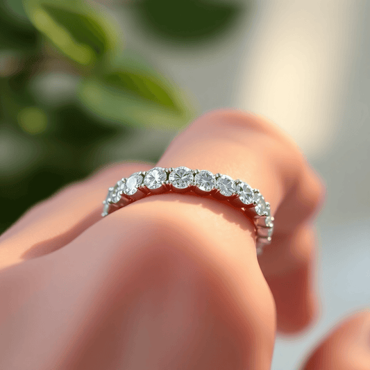 Close-up of a sparkling lab-grown diamond eternity band on a finger, with a soft glowing background featuring green leaves and sunlight.