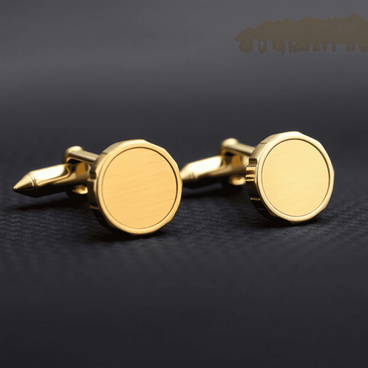 Close-up of elegant gold and silver men's cufflinks with detailed engraving on dark textured fabric background.