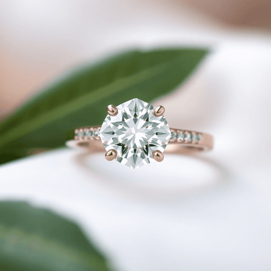 Close-up of a sparkling engagement ring with a brilliant diamond, set against a soft background with green leaves symbolizing sustainability.