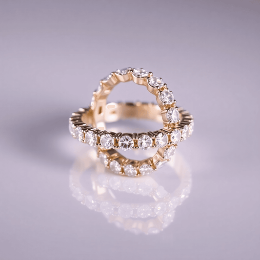 Close-up of a sparkling diamond eternity band on a reflective surface, illuminated by soft lighting that highlights the diamonds' brilliance and clarity.