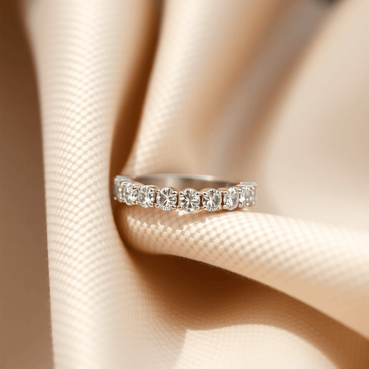 Close-up of a sparkling diamond eternity band on soft neutral fabric, illuminated by natural light showcasing its brilliance and clarity.