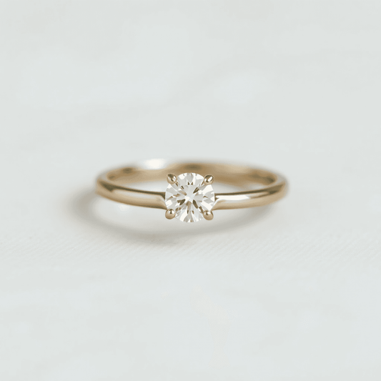 Close-up of a solitaire diamond ring on a polished band against a soft, neutral background highlighting its minimalist and timeless elegance.