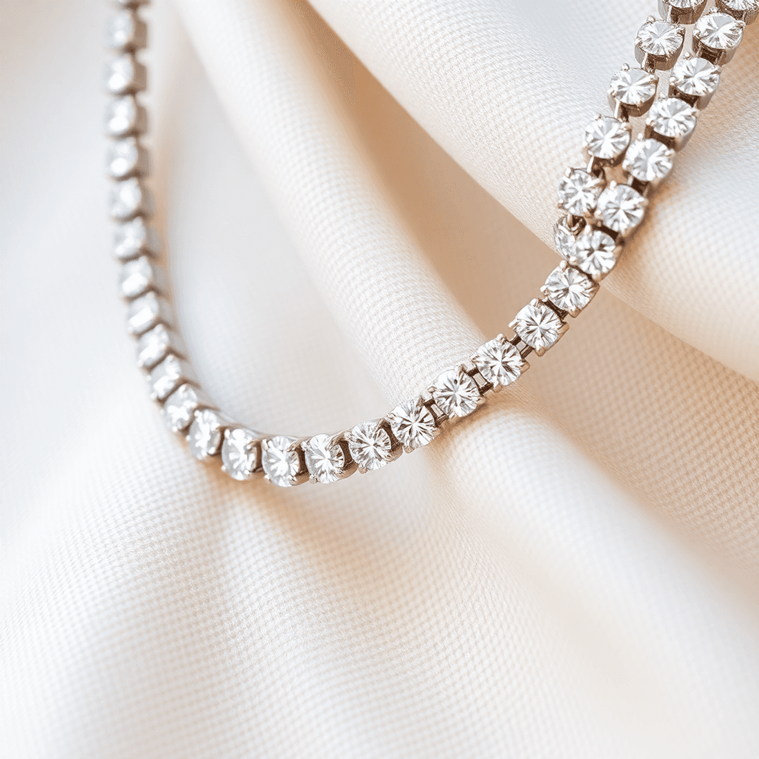 Close-up of a sparkling diamond tennis necklace on soft fabric, showcasing a continuous row of brilliant diamonds with gentle light reflections.