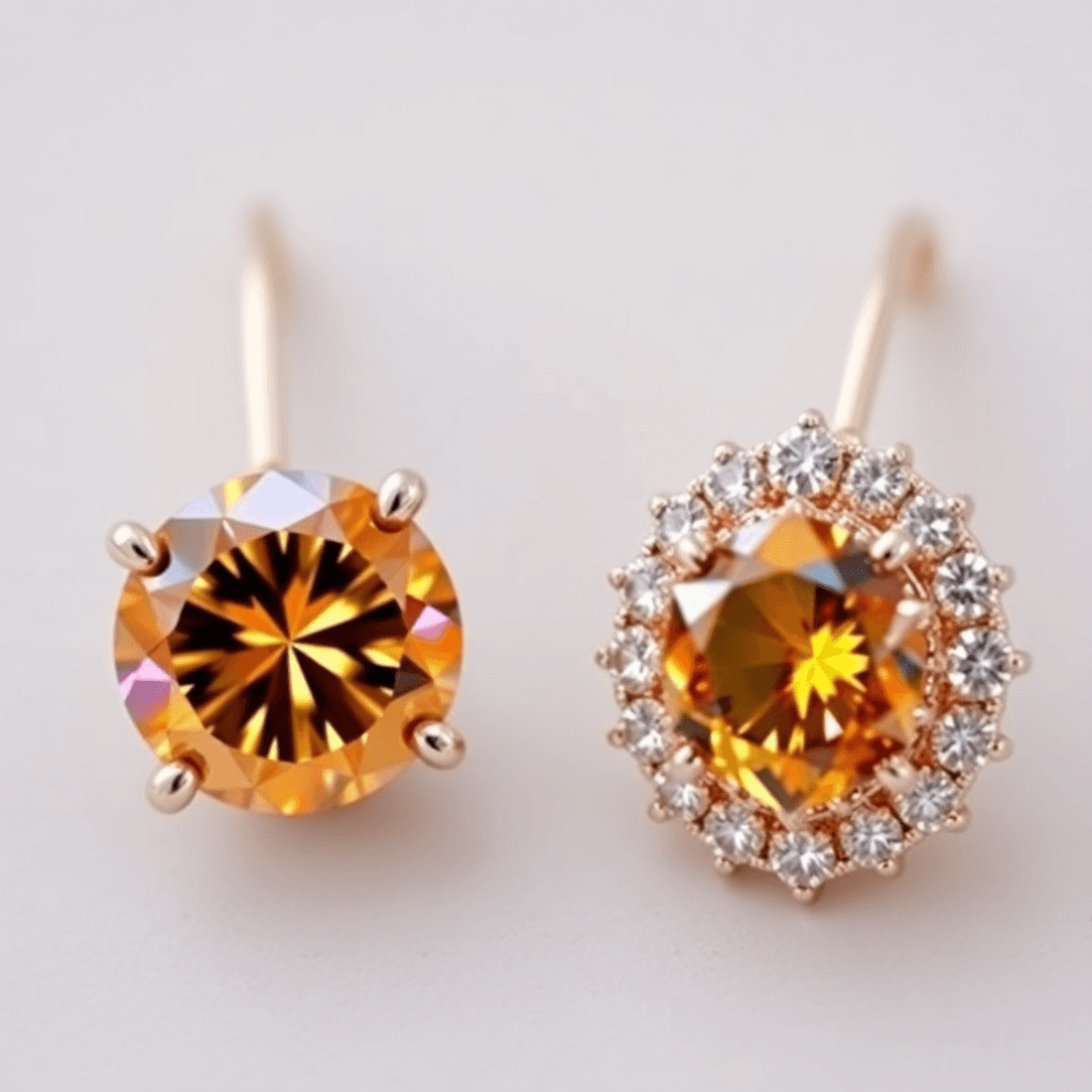 Close-up of elegant colored diamond earrings with a solitaire warm-toned diamond and a halo earring with a central colored diamond and smaller stones.