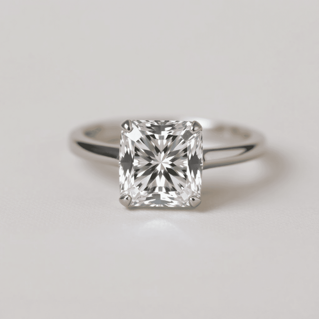 Close-up of a sparkling cushion cut diamond solitaire ring on a soft neutral background, highlighting its rounded square shape and brilliant facets.