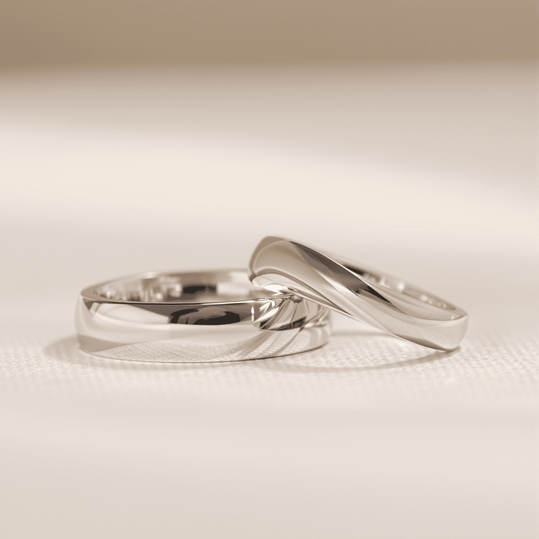 Close-up of elegant wedding bands with court and D-shape profiles on a soft background, highlighting smooth curves and polished metal surfaces.