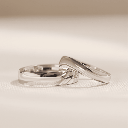 Close-up of elegant wedding bands with court and D-shape profiles on a soft background, highlighting smooth curves and polished metal surfaces.