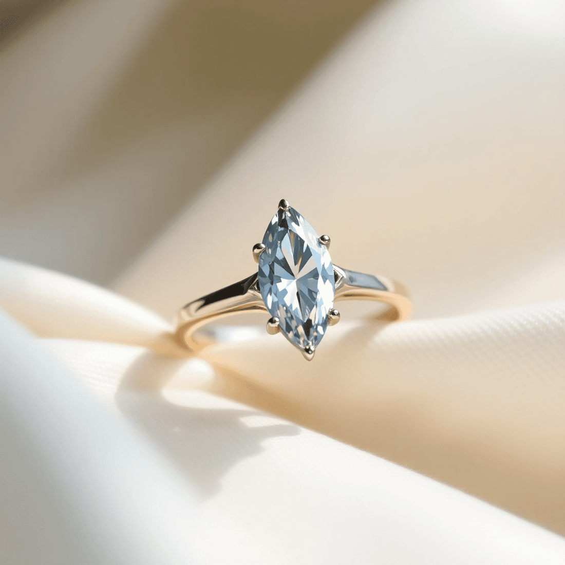 Close-up of a sparkling marquise-cut diamond ring on a sleek metal band, resting on soft fabric with natural light highlighting its brilliance.
