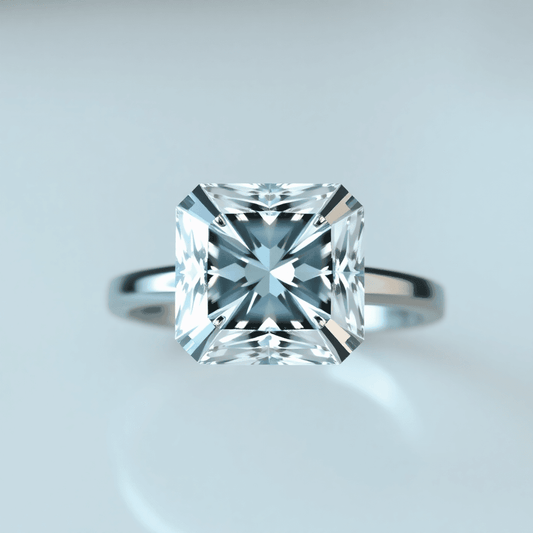 Close-up top-down view of a sparkling Asscher cut diamond on a sleek white gold or platinum ring band with soft blurred background and light reflections.