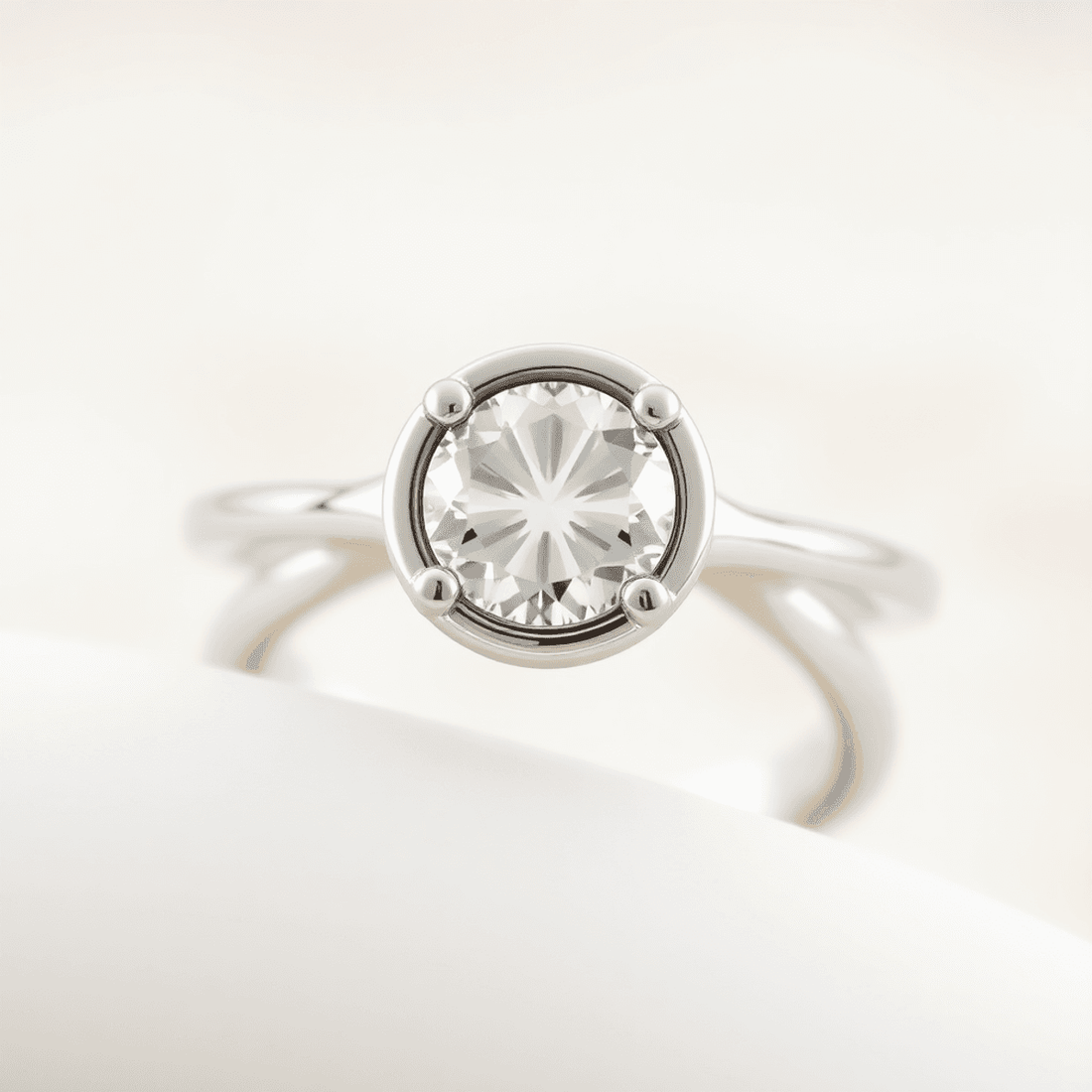Close-up of an elegant half bezel diamond ring with a sparkling center stone and hidden accent stones on a soft, neutral background.