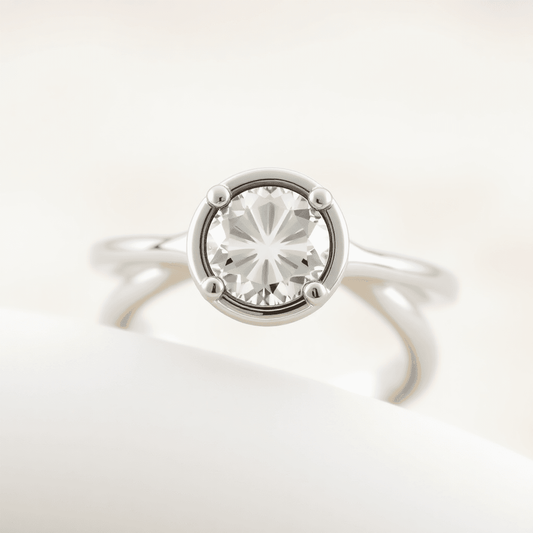 Close-up of an elegant half bezel diamond ring with a sparkling center stone and hidden accent stones on a soft, neutral background.