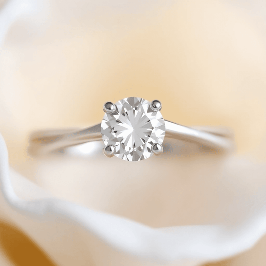 Close-up of a diamond ring with a split shank band and sparkling center stone against a soft, glowing background.