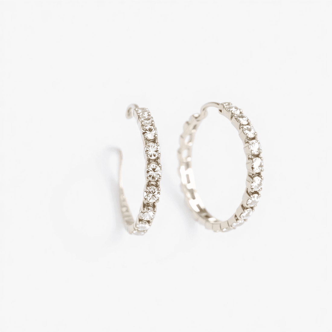 Close-up of sparkling diamond hoop earrings on a white background, showcasing their circular design and dazzling diamonds.