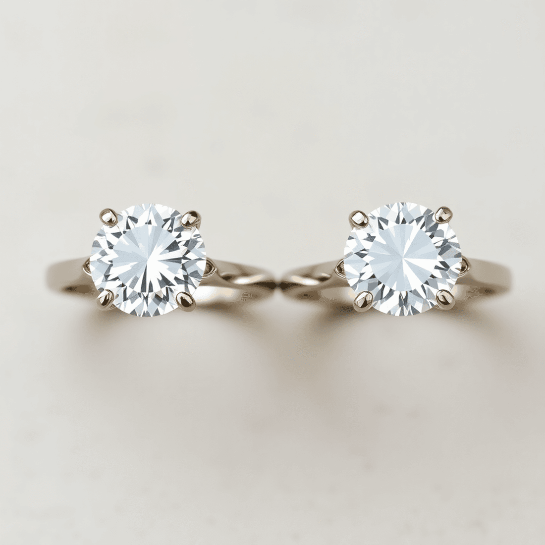 Close-up of two sparkling diamond engagement rings, one with a 3 carat and the other a 6 carat diamond, side by side on a neutral background.