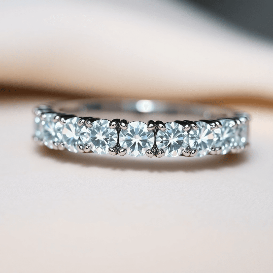 Close-up of a sparkling diamond eternity band with secure prong settings on a soft, glowing surface highlighting the brilliance of the diamonds and metal.