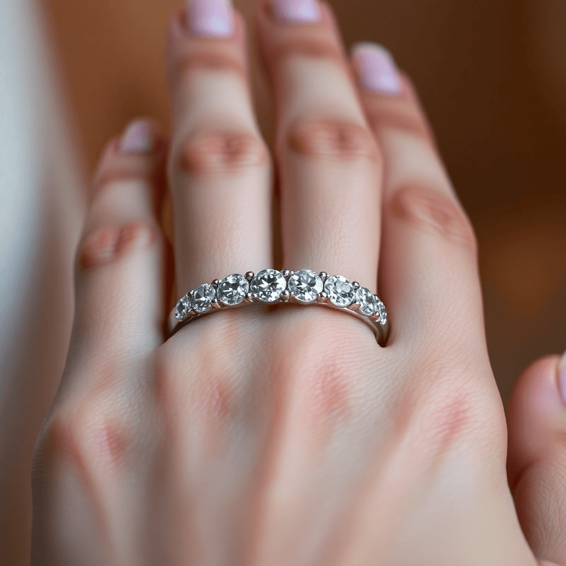Close-up of a sparkling diamond eternity band on a hand with soft warm lighting highlighting the diamonds and smooth metal band.