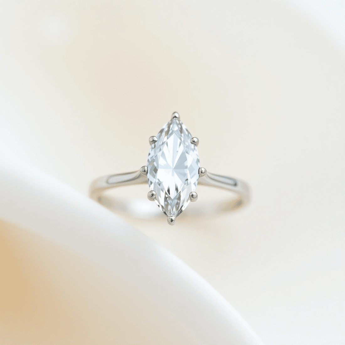 Close-up of a sparkling marquise-cut diamond ring with a minimalist design on a soft, elegant background highlighting its timeless and delicate beauty.