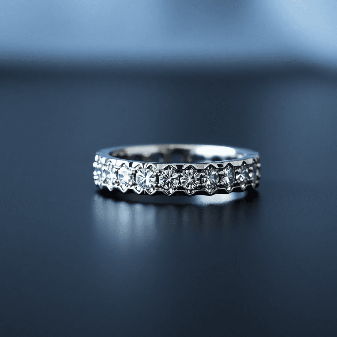 Close-up of a men's diamond eternity band on a dark surface, showcasing sparkling diamonds in a polished metal band with a softly blurred background.