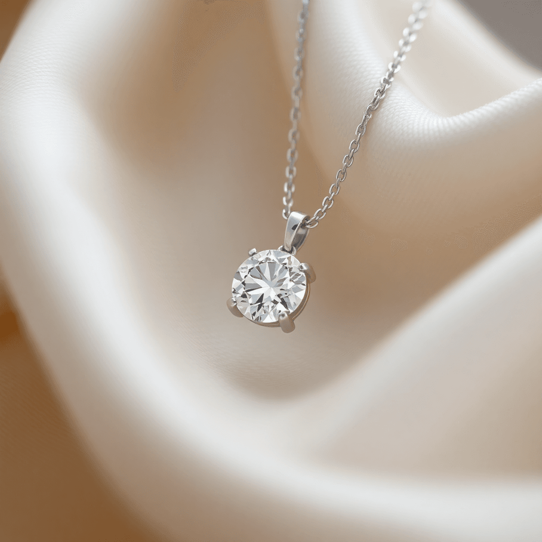 Close-up of a sparkling diamond pendant on a delicate silver chain against a soft fabric background with subtle light reflections.