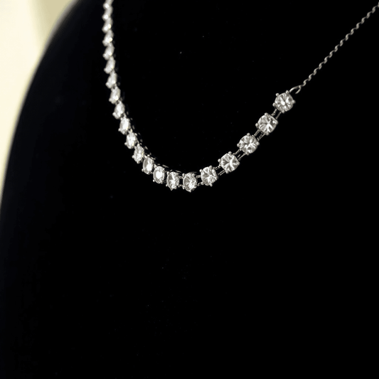 Close-up of a sparkling diamond tennis necklace on black velvet, showcasing uniform brilliance and elegance under soft lighting.