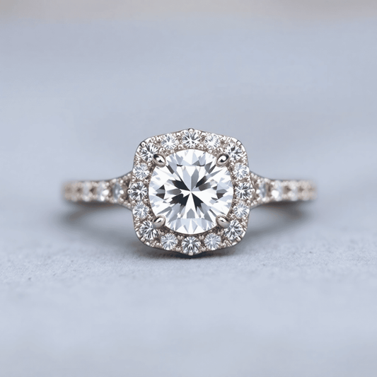 Close-up of a radiant halo diamond engagement ring with a sparkling center stone and smaller diamonds on an elegant band against a soft, blurred background.