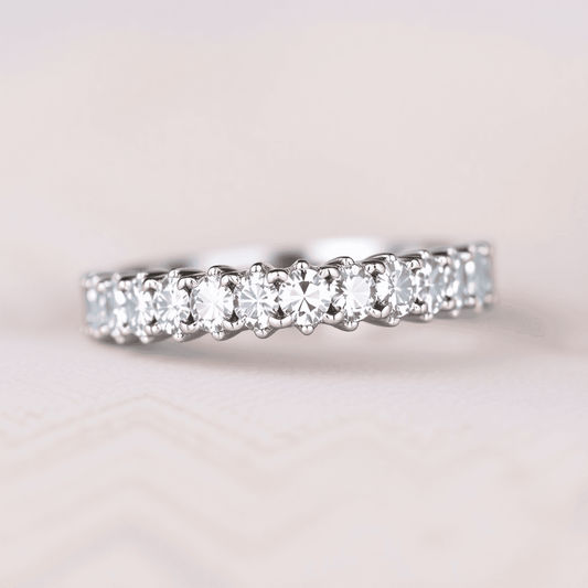 Close-up of a white gold eternity band ring with radiant diamonds on a soft, neutral background under gentle lighting.