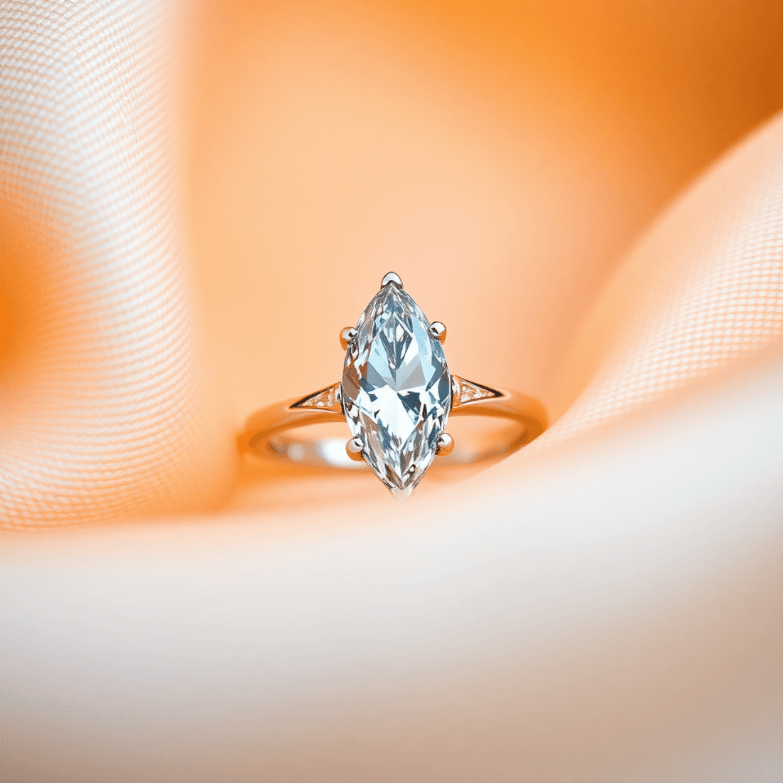 Close-up of a sparkling marquise cut diamond ring on soft fabric with warm lighting highlighting its elegant, elongated shape.