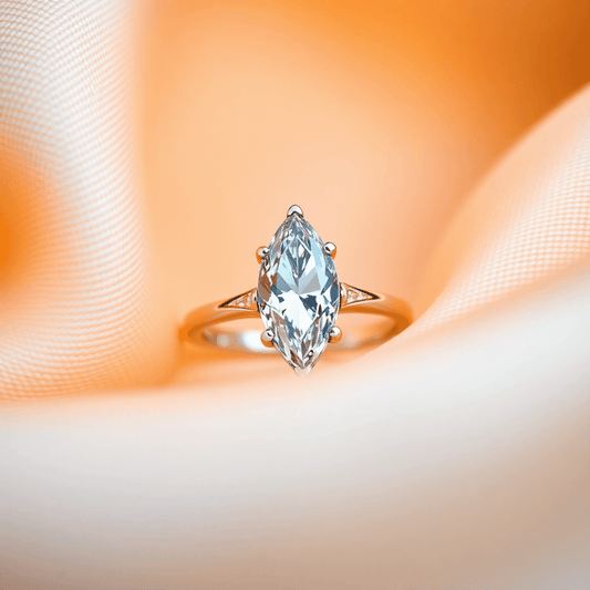 Close-up of a sparkling marquise cut diamond ring on soft fabric with warm lighting highlighting its elegant, elongated shape.