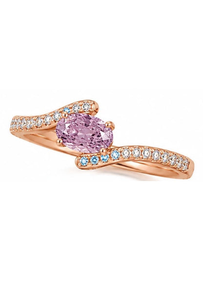 Angled view of a natural Fancy Intense Pink Purple oval diamond bypass engagement ring featuring a flowing micro pavé bypass shank with blue diamond accents.