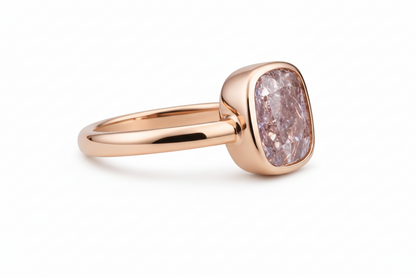 Rose gold ring with a pinkish-purple diamond on a white background